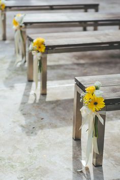 yellow and white flowers are tied to benches