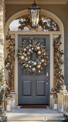 a front door decorated for christmas with wreaths and ornaments on the outside, lit by lanterns