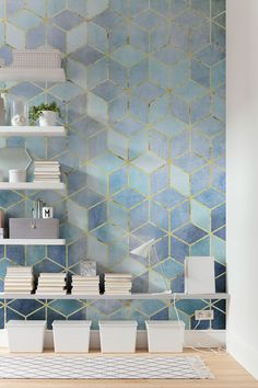 a shelf with books and vases on it in front of a blue tiled wall