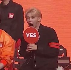 two young men holding up signs with the words yes on them in front of an orange background