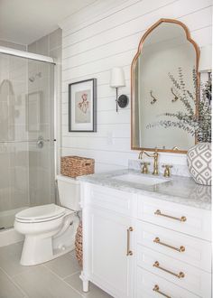 a white bathroom with gold accents and marble counter tops, along with an instagram