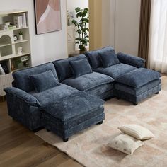 a blue sectional couch sitting on top of a rug in a living room next to a window