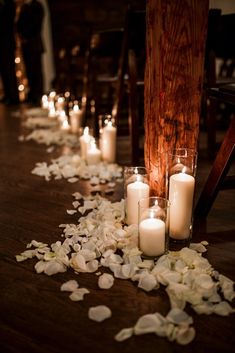 candles are lined up on the floor with petals