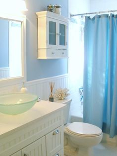 a bathroom with a sink, toilet and blue shower curtain