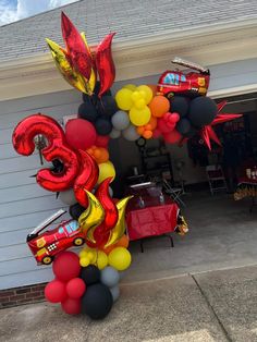 a balloon arch with cars and balloons on the front of a house for a birthday party