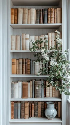 the bookshelf is filled with many different types of books and flowers in vases