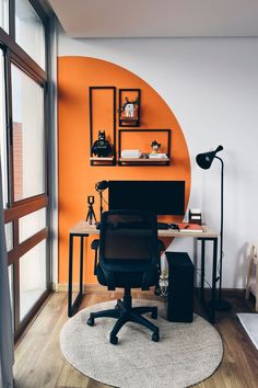 an office with orange walls and white carpeting on the floor, along with a black chair