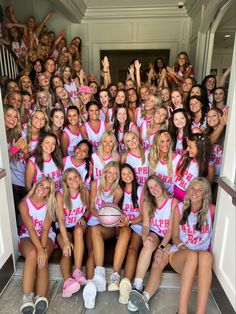 a group of girls in pink and white cheer for the camera