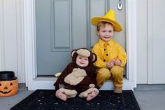 two children in costumes sitting on the front door