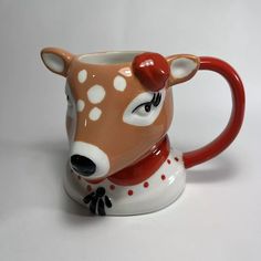 a ceramic mug with a deer's head painted on the front and sides, sitting on a white surface