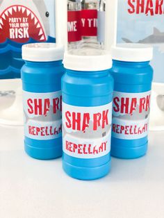 three blue bottles with shark repellant on them sitting on a table next to other items