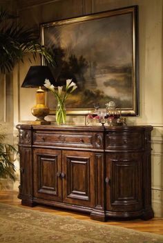 a painting hangs on the wall behind a buffet table with flowers in vases and other decorations