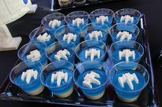 cupcakes with white frosting in plastic cups on a black tablecloth covered tray