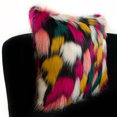 a multicolored fur pillow sitting on top of a black couch