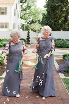 two women in grey dresses walking down a brick path