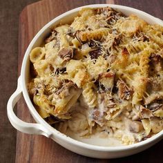 a casserole dish with pasta and mushrooms in it on a wooden board, ready to be eaten