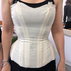 a woman is wearing a white and black dress with holes in the back, while she has her hands on her hips