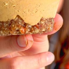 a person holding up a doughnut with peanut butter on it's top and toppings