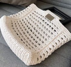 a white crocheted bag sitting on top of a couch