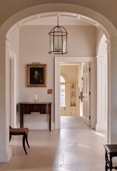 an archway leading to a hallway with a bench and table in it, along with a painting on the wall