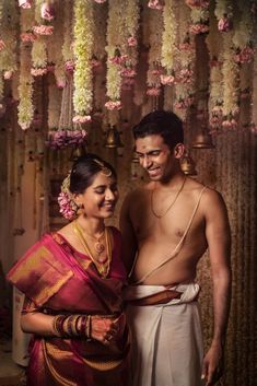 a man and woman standing next to each other in front of flowers hanging from the ceiling