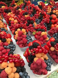 there are many different fruits in the trays on this table, including raspberries and blueberries