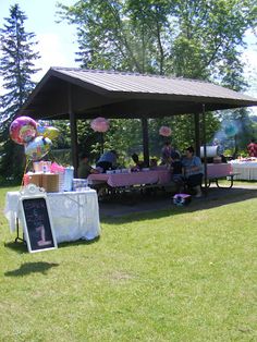 an outdoor picnic area with tables and balloons