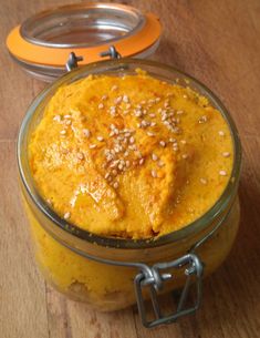 a glass jar filled with food sitting on top of a wooden table next to an orange container