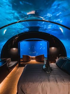 an underwater bedroom with a bed and couches under the water's blue sky