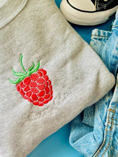 a pair of jeans and a t - shirt with embroidered raspberry on them