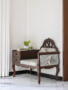 a wooden bench sitting next to a white wall with a potted plant on top of it