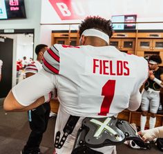 a man in a football uniform is walking through the locker room with his helmet on