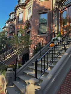 an orange pumpkin is sitting on the handrail of a set of stairs in front of a row of brownstone townhouses