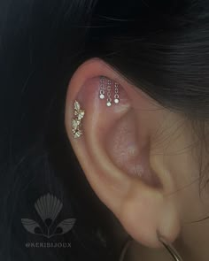 a woman's ear with three different piercings on her left side, and two smaller ones in the middle