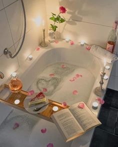 a bathtub with candles and books on the edge, surrounded by rose petal petals