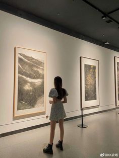 a woman standing in front of paintings on display