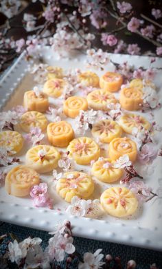 there are many small pastries on the white platter with pink and yellow flowers