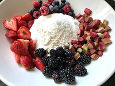 a white plate topped with berries, kiwis and other fruits next to powdered sugar