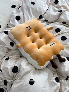 an odd shaped pillow is laying on a bed with black and white polka dot sheets