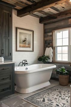 a white bath tub sitting under a window next to a rug on top of a wooden floor