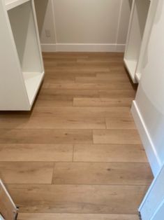 an empty closet with white walls and wooden floors