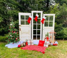 an outdoor area with christmas decorations and stockings hanging on the door, trees in the background