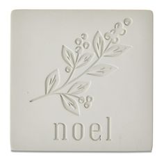 a white tile with the word noel written on it and an image of a plant