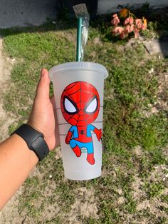 a hand holding a plastic cup with spiderman on it