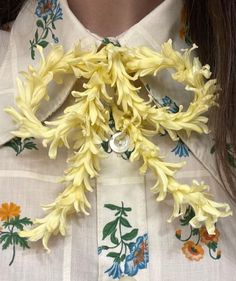 a woman wearing a white shirt with yellow flowers on it