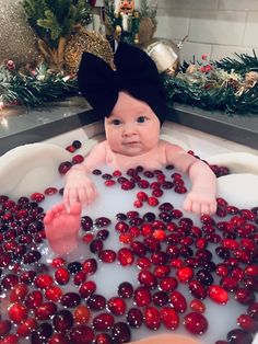 a baby sitting in a bath filled with cherries