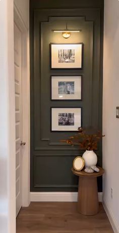 a hallway with pictures on the wall and a vase filled with flowers