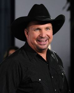 a man wearing a black cowboy hat smiles at the camera