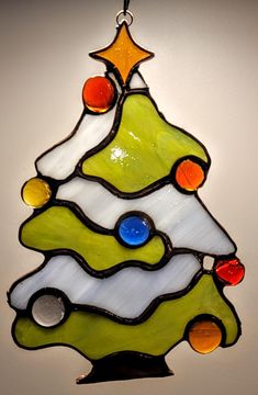 a stained glass christmas tree ornament hanging on a wall