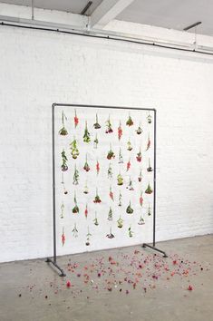 a white wall with flowers hanging from it's sides in front of a black metal frame